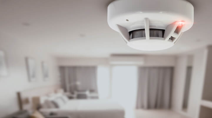 A carbon monoxide detector in the ceiling of a bedroom. 