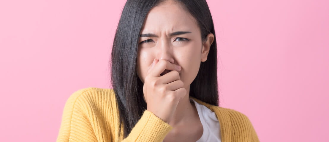 A person plugging their nose while grimacing.
