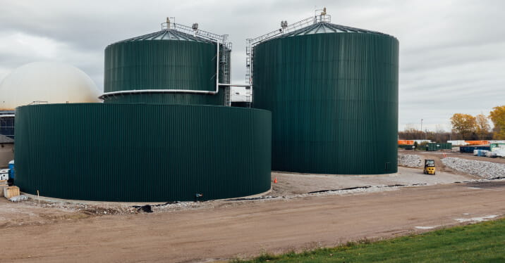 Outdoor view of dark green anaerobic digesters at StormFisher biogas facility in London, Ontario.