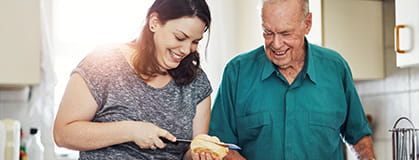 Elderly father and daughter cooking in kitchen.