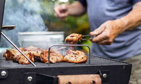 A man preparing barbecue grill for garden party.