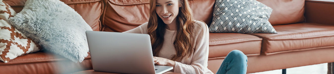 Young woman using laptop while sitting on floor in living room