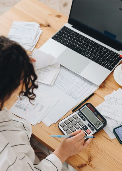 Top view of a woman working at home in the kitchen paying bills and planning a budget to save some money.