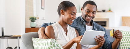 Couple on their bank website with a credit card at home