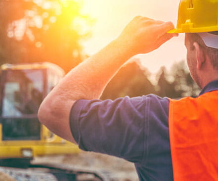 A person wearing safety gear, overseeing a safe excavation on a construction site.