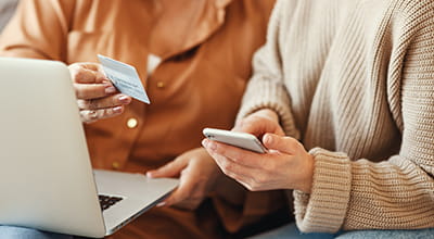Women using laptop and smartphone doing online shopping and holding their credit card