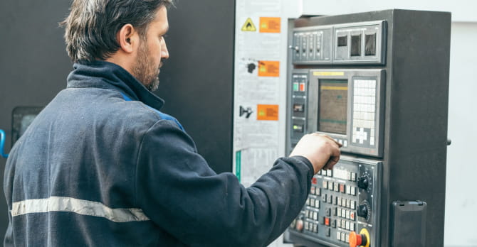 Man standing in front of programmable machine in factory