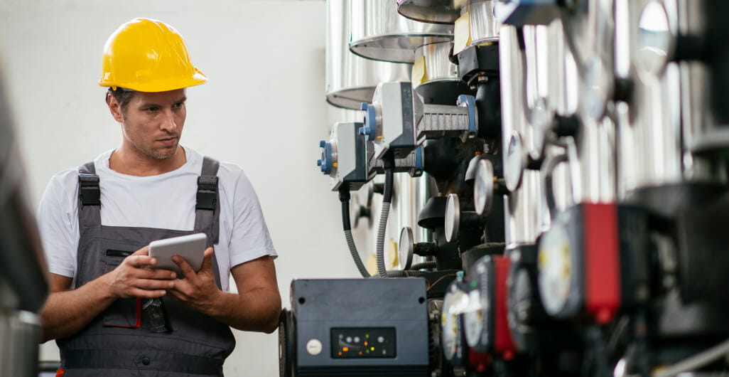 Man with hard hat holding tablet and examining Natural gas machines