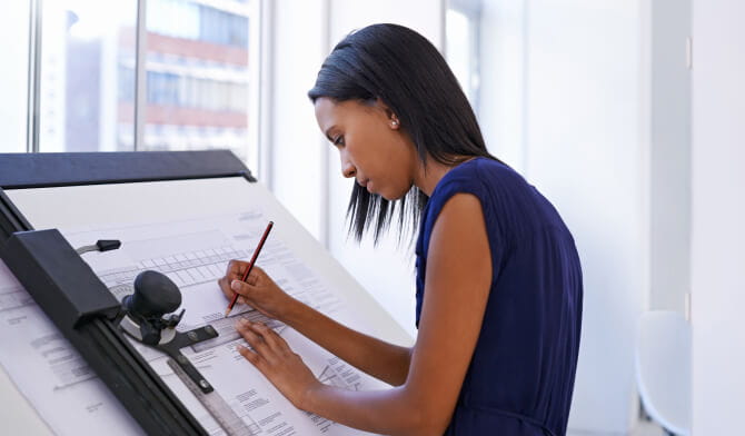 Woman standing at drawing board looking at blueprints