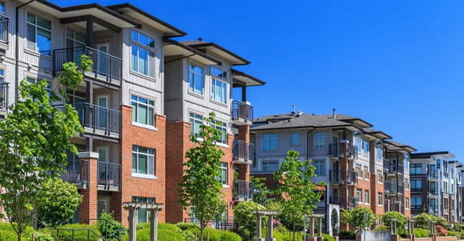 Exterior view of a four storey modern condominium development on a clear day. 