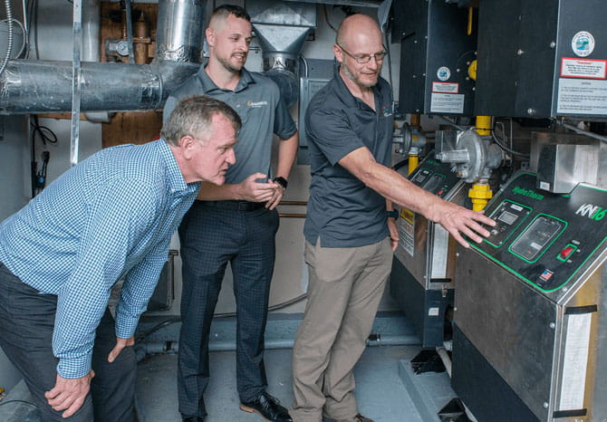A group of men standing next to a machine.