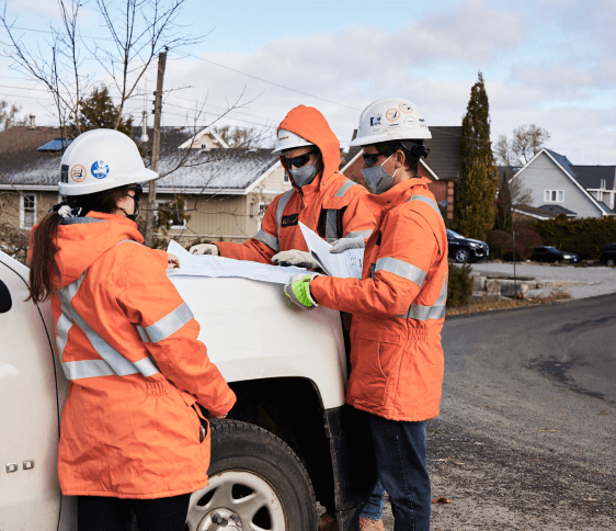 Three gas technicians in hard hats inspecting plans.