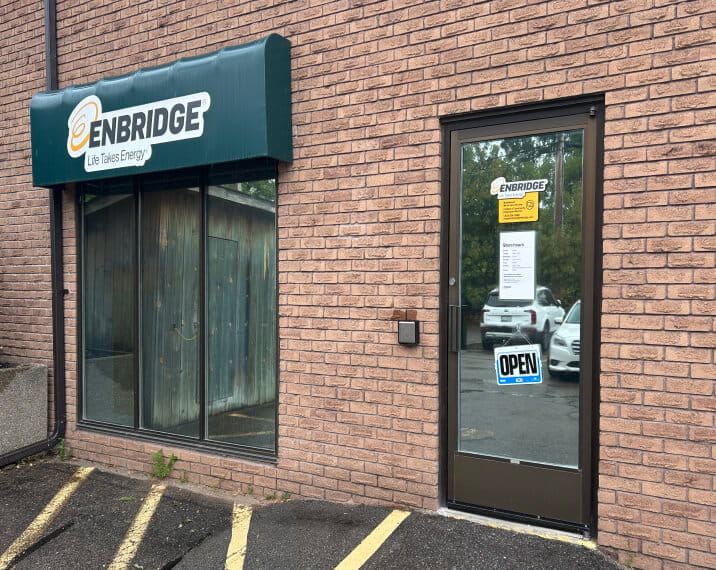 Storefront in a brick building with an Enbridge Gas–branded awning and an “Open” sign on the door.