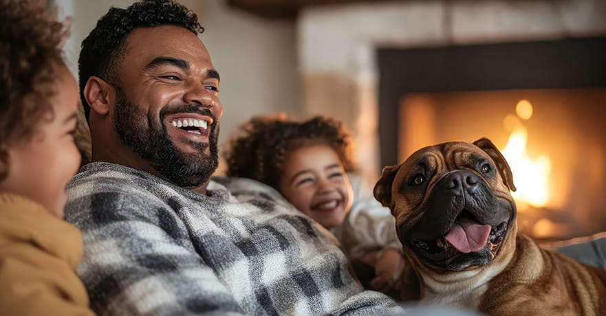 A diverse family shares a hearty laugh at home by the warm fireplace.