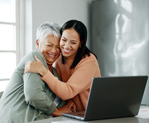 Mother and woman hugging and a laptop 