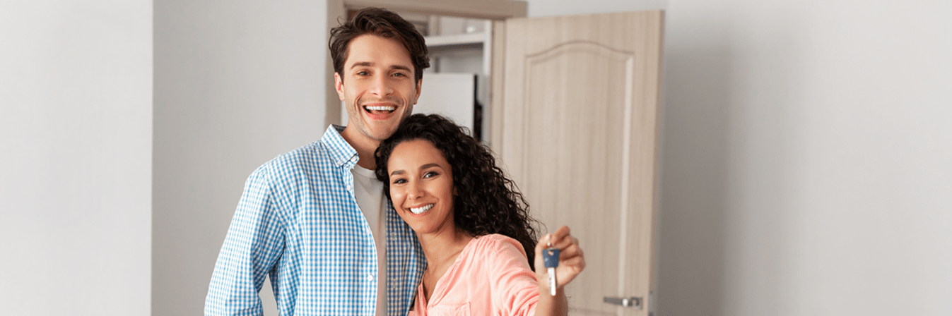 A couple holding a key in a room with boxes