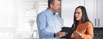 Two people discussing with a hand-held digital screen